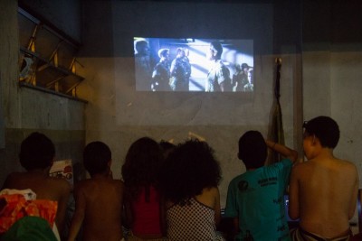 Crianças assistem filme projetado na parede da Ocupação Vito Giannotti